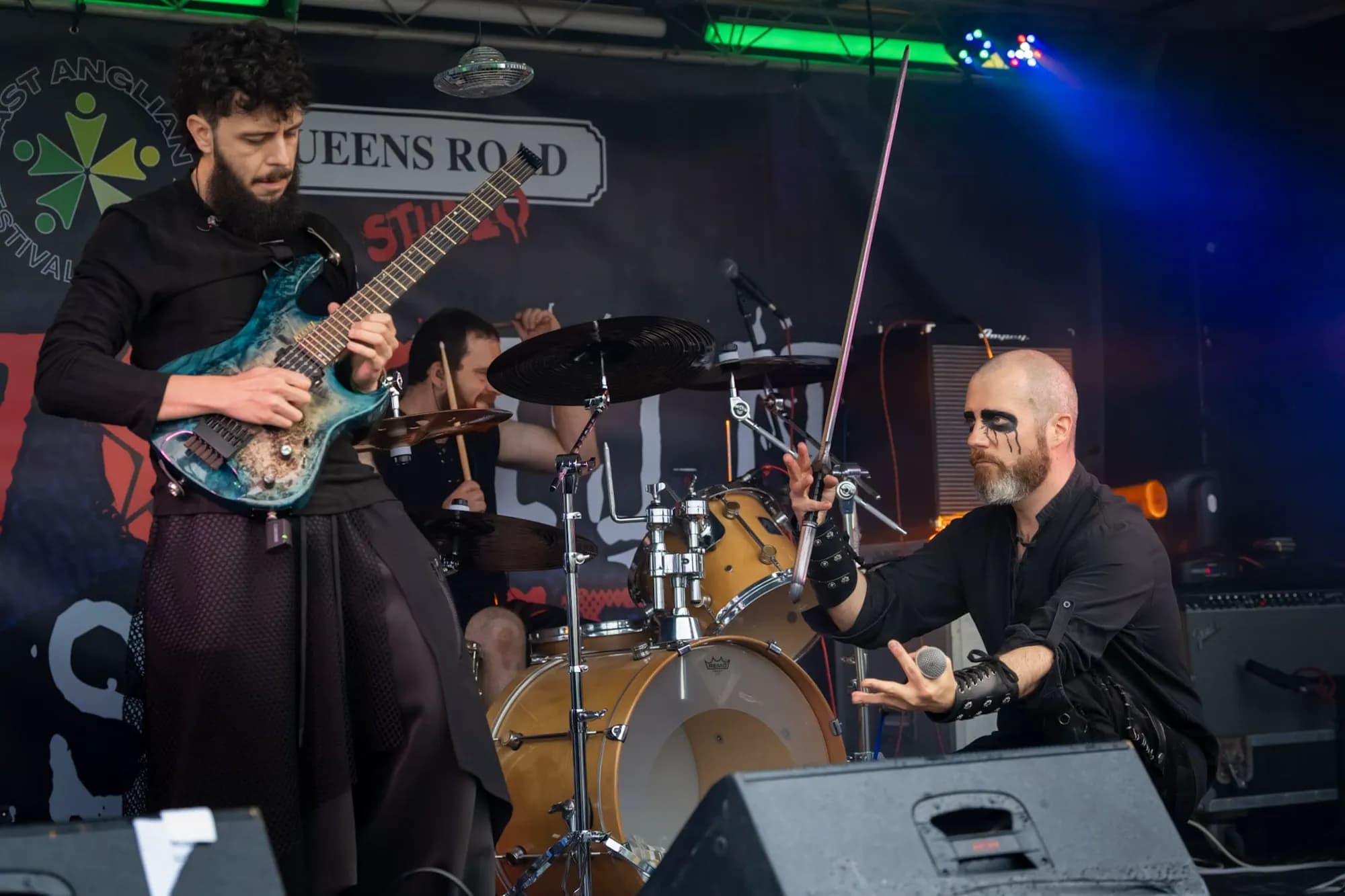 Shadow Fen mid-song on a daytime festival stage - the guitarist deep in a solo as the vocalist levels a sword across the boards.